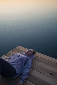 Low section of woman sitting on pier over lake