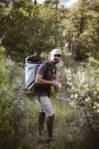 Portrait of hiker holding chalk powder container while standing on field in forest