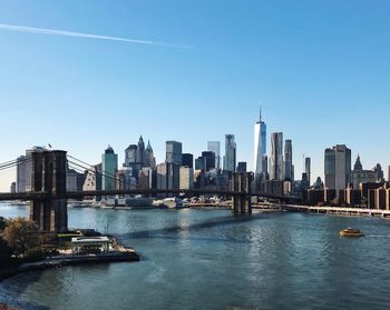 Brooklyn bridge and east river against blue sky in city