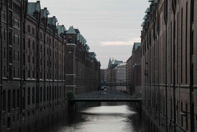 Canal amidst buildings against sky in city