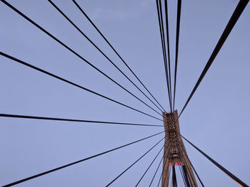 Low angle view of cables and bridge pylon against sky