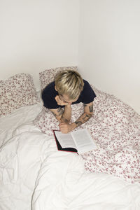 Woman reading book on bed at home
