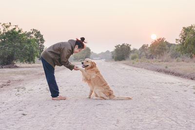 Man with dog on road against sky