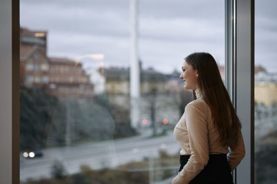 Young businesswoman looking through window