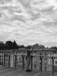 Rear view of woman standing by railing against sky