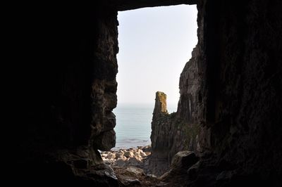 Rock formations by sea against clear sky