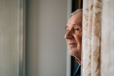 Side view of man looking through window