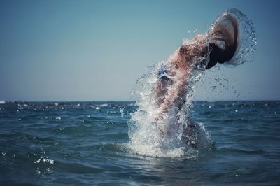 Water splashing in sea against clear sky