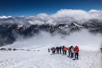 People on snowcapped mountains against sky during winter