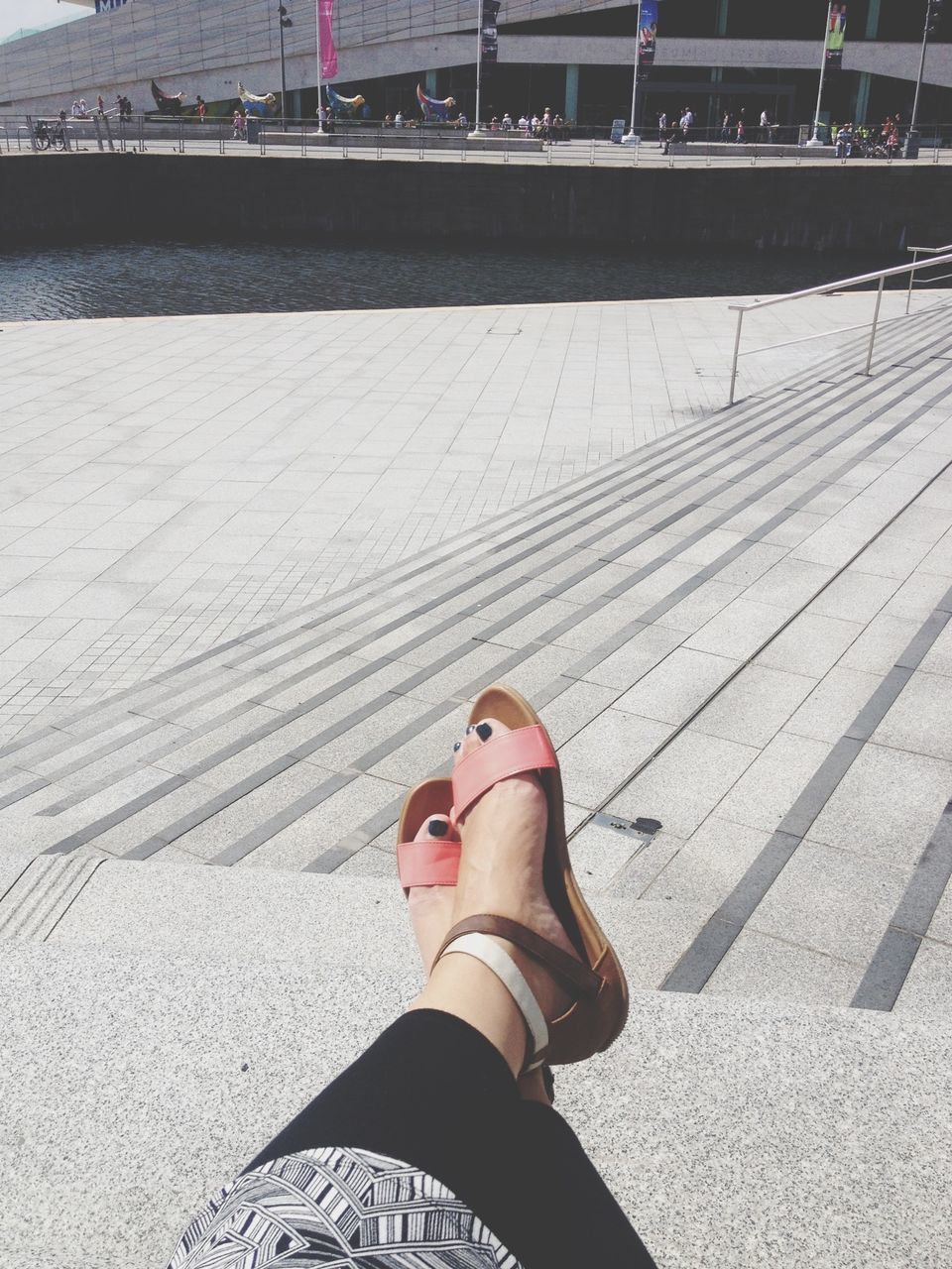 lifestyles, low section, person, leisure activity, high angle view, standing, sunlight, shadow, day, street, outdoors, casual clothing, shoe, personal perspective, men, pier, sitting