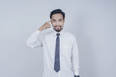 Portrait of young man standing against white background