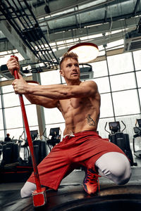 Rear view of shirtless man exercising in gym