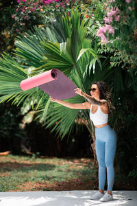 Woman holding umbrella standing against plants