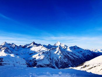 Scenic view of snowcapped mountains against blue sky