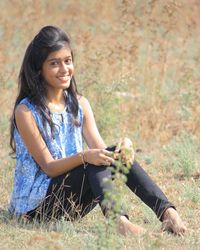 Young woman using phone while sitting on grass