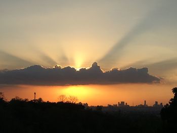 Silhouette trees and buildings against sky during sunset