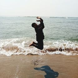 Full length of shirtless man at beach against sky