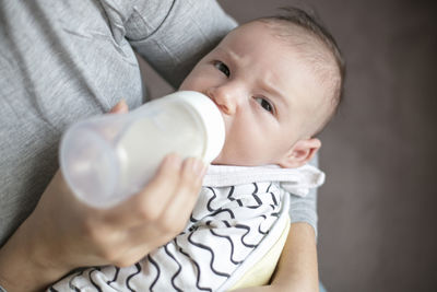 Cropped image of mother feeding milk to baby boy
