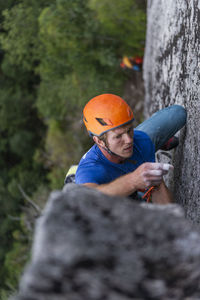 Close-up of man lead climbing and placing gear with helmet and focus