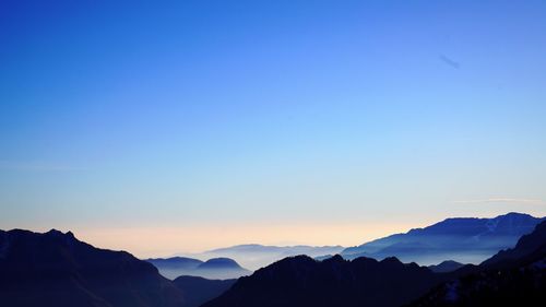 Scenic view of silhouette mountains against clear sky at sunset