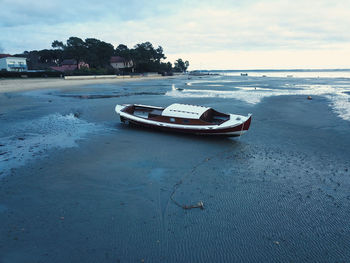 Boat moored on beach against sky