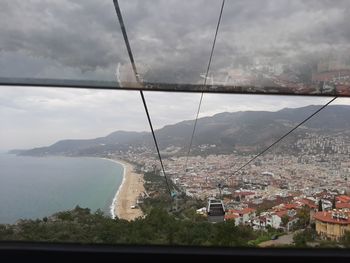 Overhead cable car over sea and buildings against sky