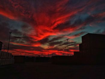 Silhouette buildings against dramatic sky during sunset