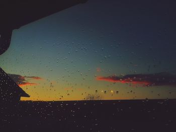 Raindrops on glass window during sunset