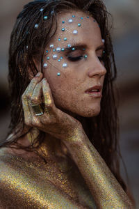 Portrait girl in gold glitter on the background of the stones