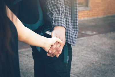 Midsection of couple holding hands