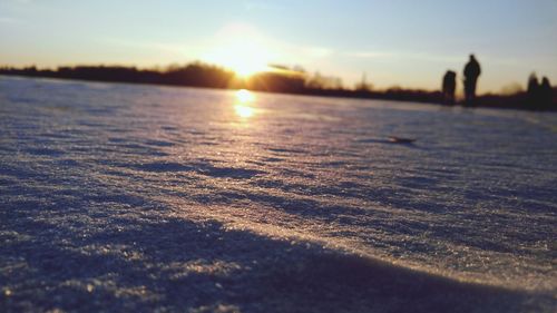 Close-up of frozen lake against sky during sunset