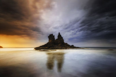 Scenic view of rocks in sea against sky during sunset