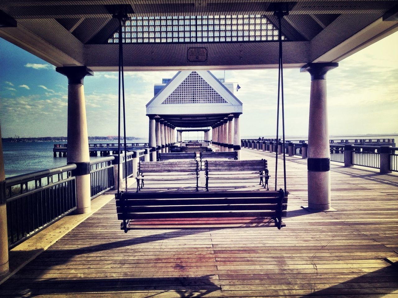 sea, pier, built structure, water, railing, architecture, sky, horizon over water, the way forward, gazebo, wood - material, tranquility, empty, tranquil scene, sunlight, nature, architectural column, scenics, boardwalk, shadow