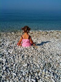 Full length of young woman standing on pebbles at beach