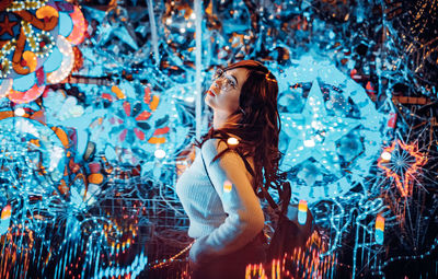 Young woman standing against illuminated wall