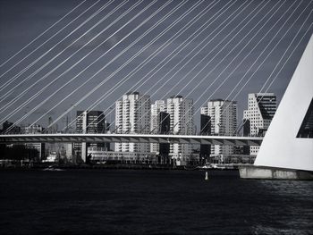 Bridge over sea by buildings against sky in city
