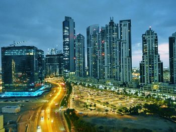 Traffic on road by illuminated buildings against sky at night