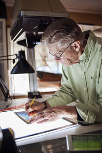 Senior man drawing on graphics tablet at home