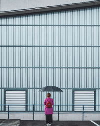 Portrait of woman standing against pink wall