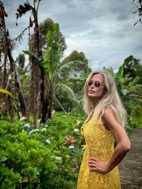 Portrait of young woman standing against trees