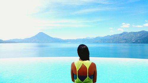 Rear view of woman by sea against sky