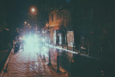 Illuminated street in city during winter