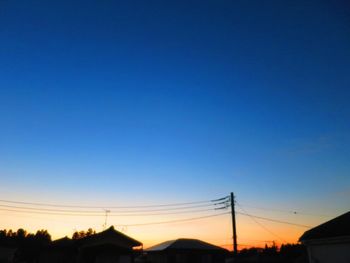 Silhouette of electricity pylons against clear blue sky