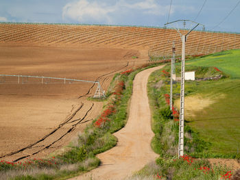 Road amidst field against sky