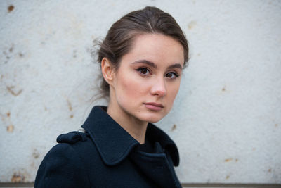 Portrait of young woman against wall