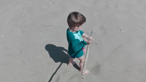 High angle view of boy playing with stick on shore at beach