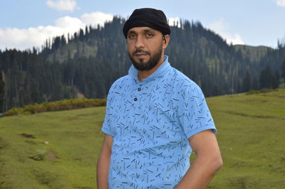 Portrait of young man standing on grassy field 