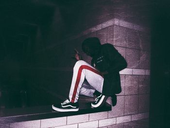 Low section of man sitting against wall