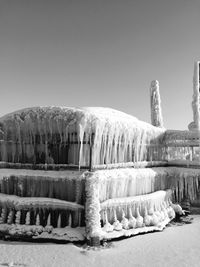 Frozen landscape against clear sky during winter