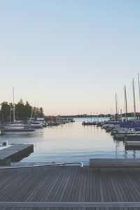 Boats moored at harbor against clear sky